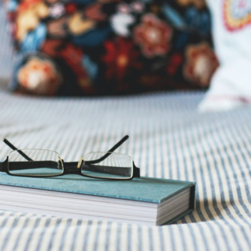 Book and reading glasses on a bed